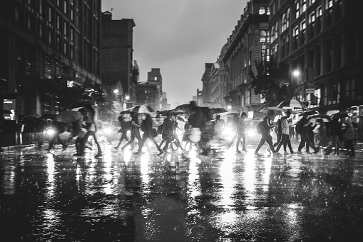 Commuters cross 6th Avenue in Manhattan on a rainy night
