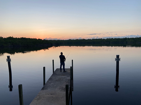 Man fishing off a dock during sunrise at Everglades National Park