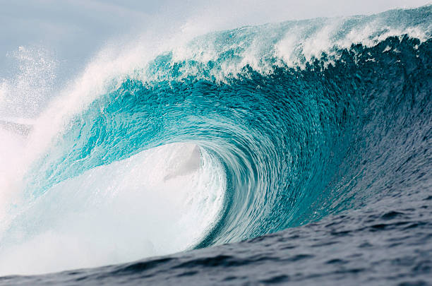 Amazing Nature A perfect turquoise wave roars towards the coast. tsunami wave stock pictures, royalty-free photos & images