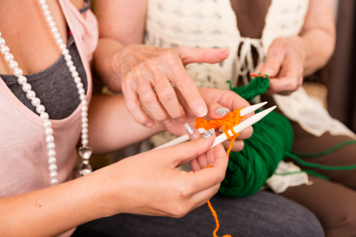 Arts Crafts: Senior Woman shows Young Adult how to knit.