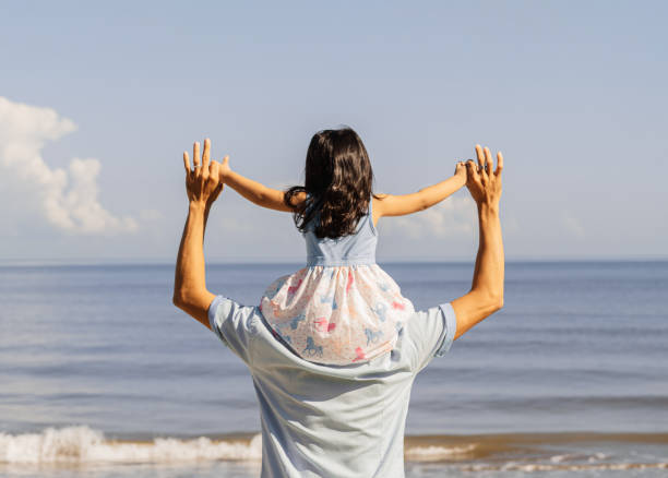 istock Fun father holding a his daugther over head walking to a beach. 1705073967