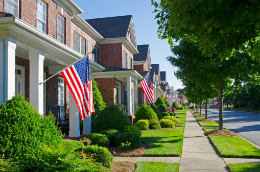 American Flags hang from the front of this traditional, brick homes in an All-American neighborhood.