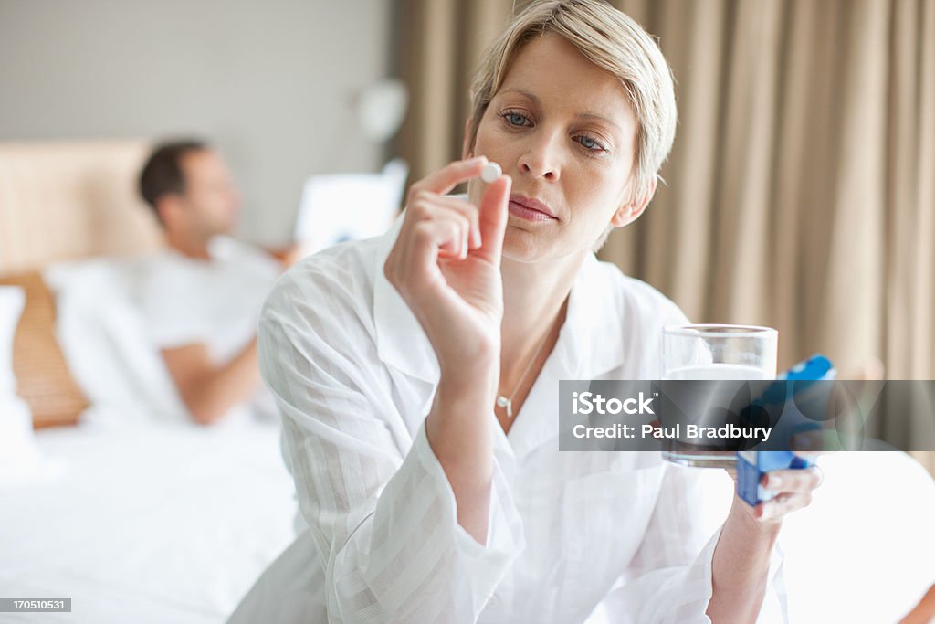 Kobieta trzyma tabletkę z lekami - Zbiór zdjęć royalty-free (Brać lekarstwo)