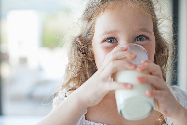 bambina bere un bicchiere di latte - milk foto e immagini stock