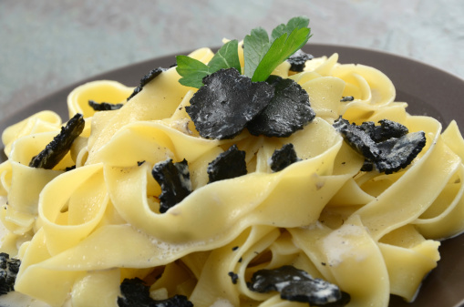 An indulgent dish of pappardelle pasta with sliced black truffles and truffle-infused cream sauce.