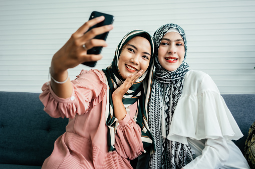 Two friends muslim are taking a selfie in living room