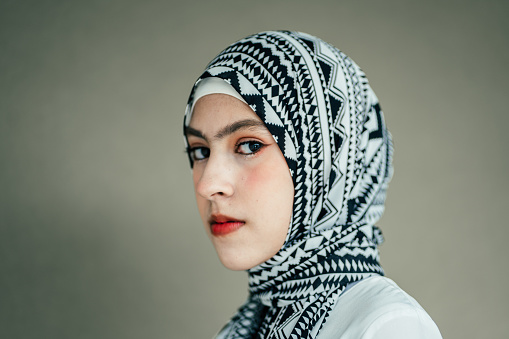 Portrait of confident Muslim teenage girl looking camera on green background