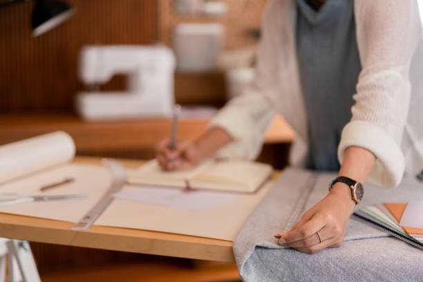 istock Asian tailor women measuring piece textile fabric and taking notes while designing new collection 1705182682