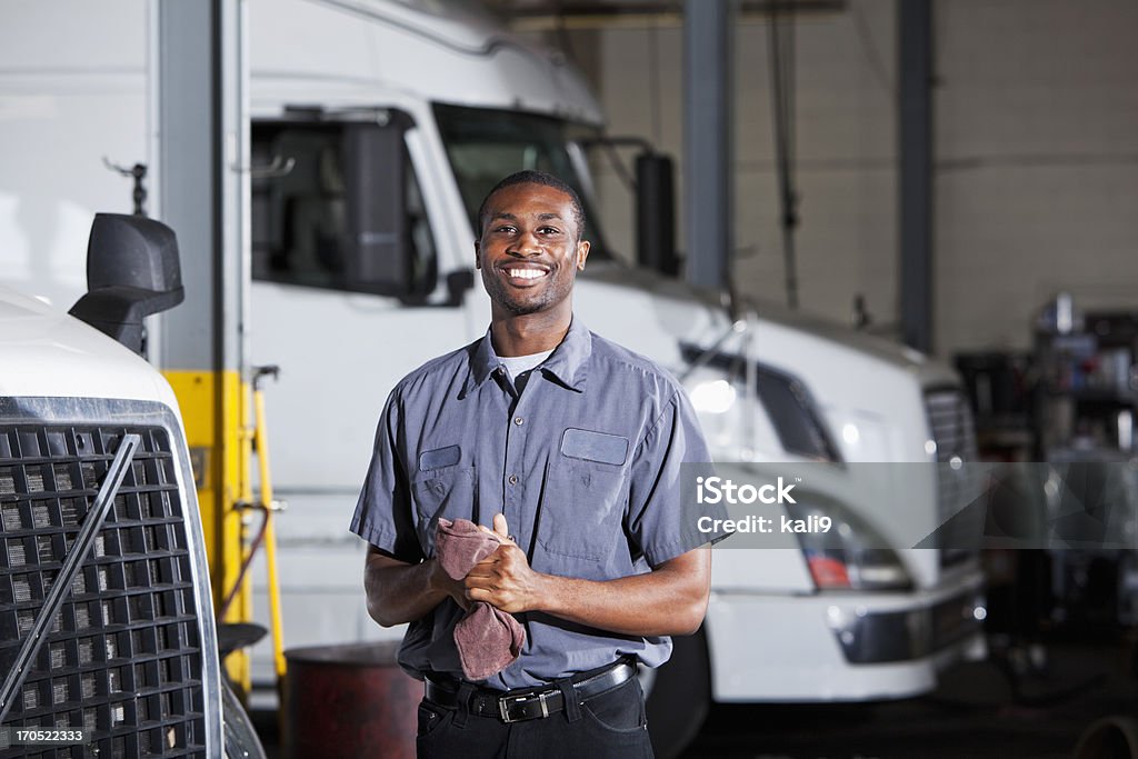 Mechanic in garage with semi-truck African American man (20s) in service garage repairing semi-trucks. Mechanic Stock Photo