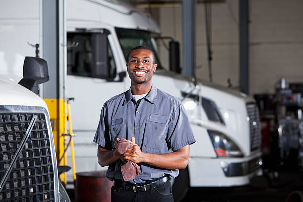 Mechanic in garage with semi-truck African American man (20s) in service garage repairing semi-trucks. mechanic stock pictures, royalty-free photos & images