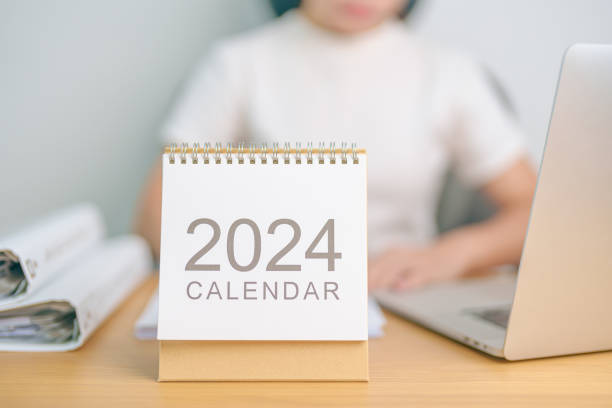 istock 2024 Year Calendar on table with business woman using laptop computer. countdown, Happy New Year, Resolution, Goals, Plan,  Action, Mission and financial Concept 1705248767