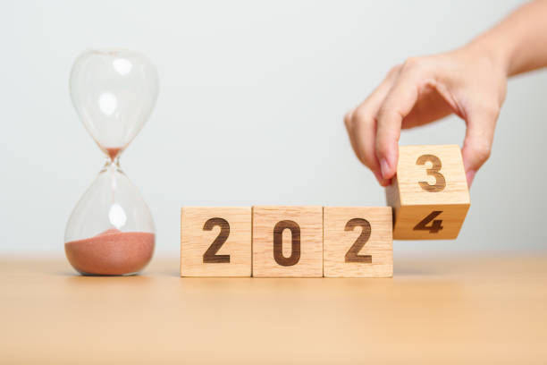 istock hand flipping block 2023 to 2024 text with hourglass on table. Resolution, time, plan, goal, motivation, reboot, countdown  and New Year holiday concepts 1705250333