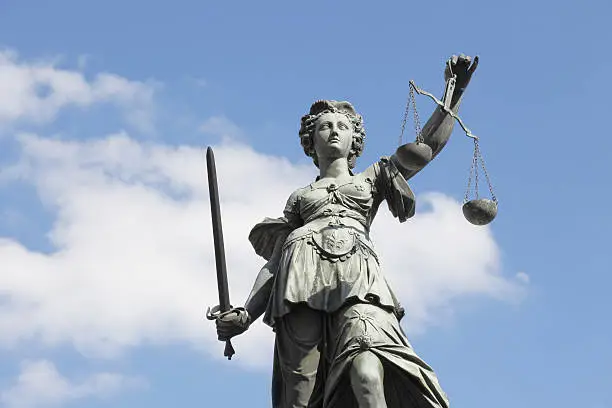 Photo of sword and cloudy  blue sky with ancient lady Justice Justitia