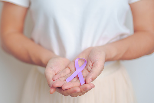 woman holding Purple Ribbon for Stomach, Violence, Pancreatic, Esophageal, Testicular cancer, Alzheimer, epilepsy, lupus, Sarcoidosis and Fibromyalgia. Awareness month and World cancer day concept