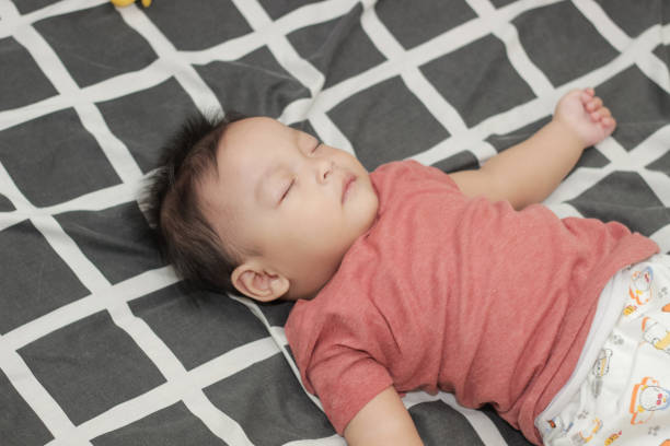High angle shot of lovely Asian newborn baby boy sleeping soundly in the crib at home