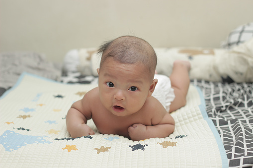 Asian baby having tummy time on mattress
