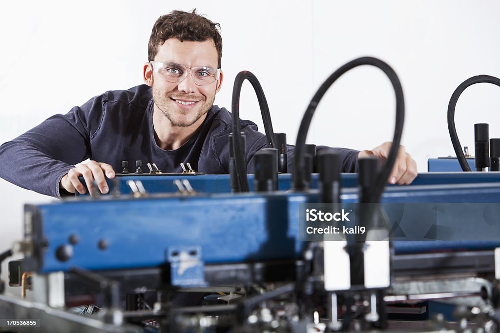 Homem operação de equipamentos de impressão de tela - Foto de stock de Impressora - Maquinaria de fábrica royalty-free