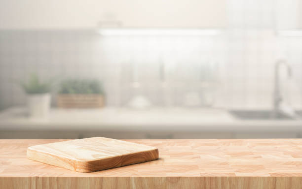 istock Selective focus.End grain wood counter top with cutting board on blur kitchen in morning window background. 1705394462