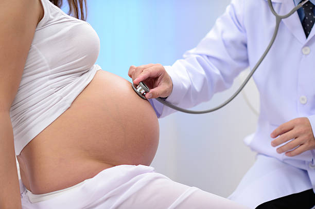lekarz słuchać brzuch w ciąży kobieta big - human pregnancy abdomen naked human hand zdjęcia i obrazy z banku zdjęć