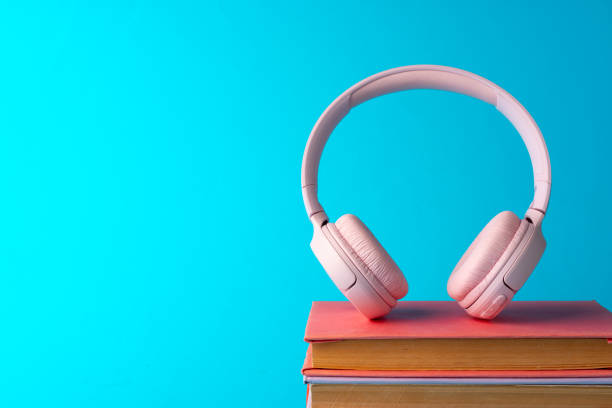 istock Pink headphones on a book on blue background 1705430527