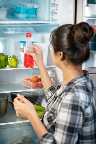 istock Woman taking a soft drink bottle from the fridge. 1705440192