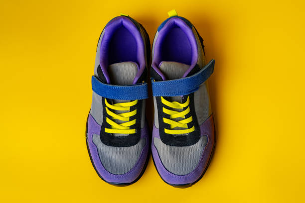 istock Violet-blue female sneakers on yellow studio background 1705449259