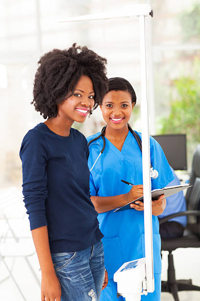 afrikanischen krankenschwester patienten, die messung größe und gewicht - tall human height women measuring stock-fotos und bilder