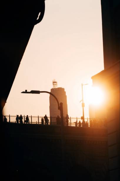 A group of people walking along a bridge during a beautiful sunset
