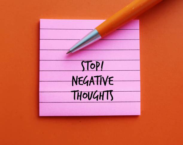 istock Pink note on orange background with pen written STOP NEGATIVE THOUGHTS, means stop mind from attracting negative life experiences, overcome and remove negative thinking and try not attract more painful events 1705488557