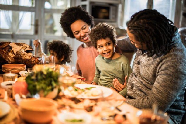 istock Happy black boy enjoying with his parents during Thanksgiving dinner at dining table. 1705503394