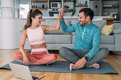 Couple giving each other high five after a successful workout at home.