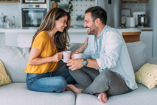 Shot of a young couple having coffee while relaxing on the sofa at home.