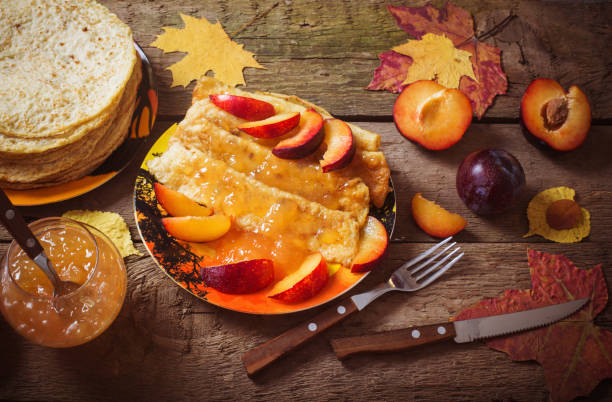 pancakes with jam and plums on wooden table