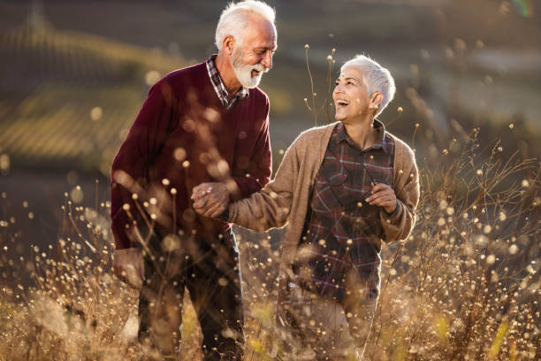 istock Cheerful mature couple talking while walking through tall grass in nature. 1705518173