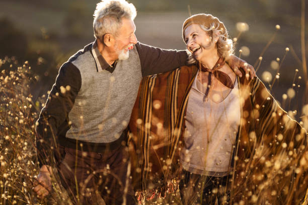 istock Happy mature couple talking while walking through tall grass in nature. 1705519769