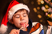 Cute little boy in Santa Claus hat eating lollipop