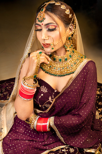High angle Portrait of beautiful traditional Indian bride wearing lehenga and jewelry on her wedding day.