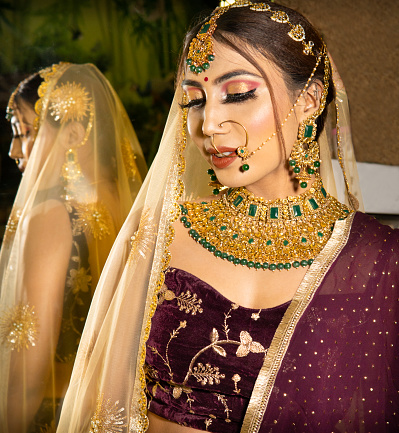 High angle Portrait of beautiful traditional Indian bride wearing lehenga and jewelry on her wedding day.