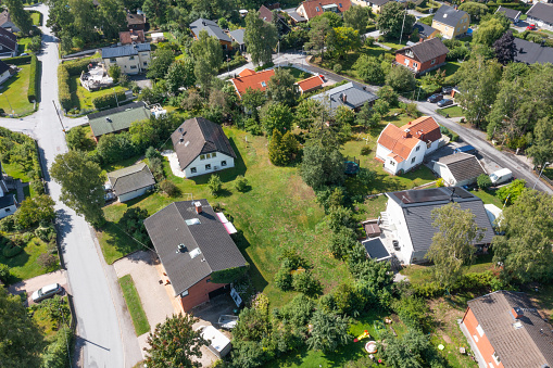 Taken from a high vantage point, this aerial view captures the essence of summer in a suburban villa community. Lush green lawns, well-manicured gardens, and tree-lined streets make this a picturesque setting. The layout of the villas and the natural surroundings present a balanced and tranquil environment. This footage is perfect for anyone involved in real estate, community planning, or environmental studies.