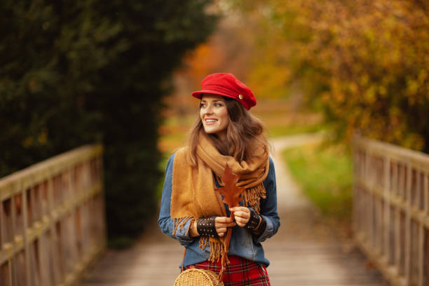 smiling elegant woman in jeans shirt and red hat stock photo
