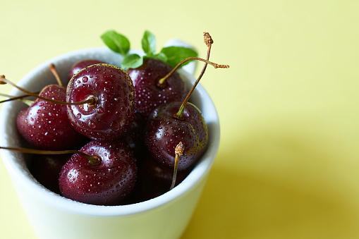 Cherries in a bowl on a yellow background. Selective focus.