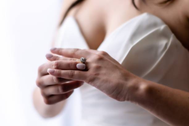 istock Bride in a white dress tenderly touching a silver diamond engagement ring 1705577174