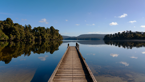 A pier stretches out over Lake Mapourika, on the West Coast of New Zealand's South Island.