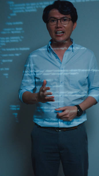 istock Closeup young Asian man software developers mentor leader manager talking to executive team analyzing source code in office at night. Programmer development. Vertical Screen. 1705602380