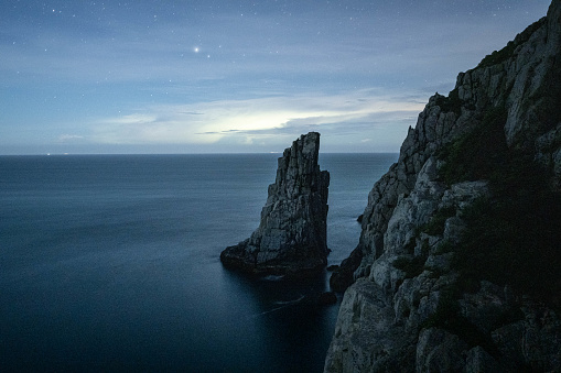 Amidst the starry canvas, a lone sea stack stands resilient against the elements. This solitary rock formation, sculpted by nature's forces over time, symbolizes the quiet strength and enduring beauty found in remote, natural landscapes, creating a captivating and contemplative scene beneath the celestial expanse.