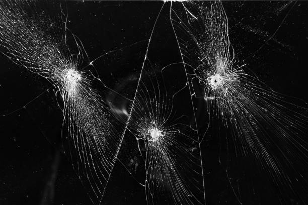istock Broken glass with bullet holes texture on black background 1705628073