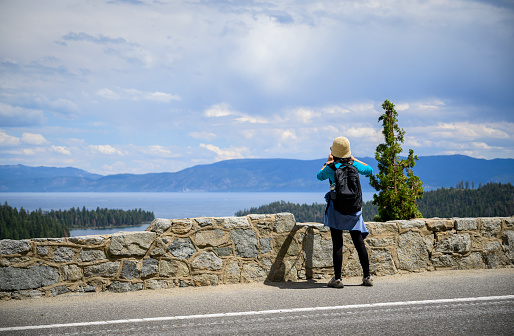 Woman taking photos using smartphone at Emerald Bay. Lake Tahoe. California.