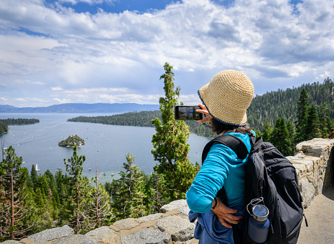 Woman taking photos using smartphone at the lookout. Emerald Bay. Lake Tahoe. California.