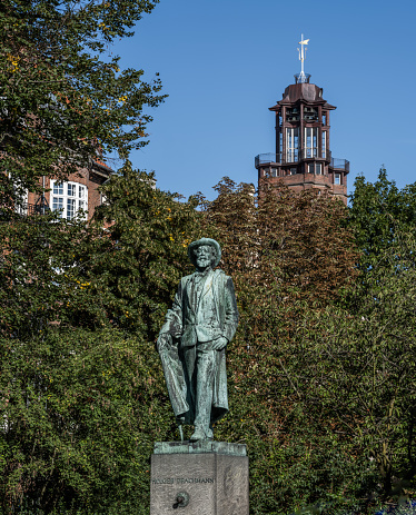Copenhagen, Denmark - September 24, 2023: Statue of the Danish poet, Holger Drachmann (1846-1908) in a park in Frederiksberg. Frederiksberg Townhall in the back.