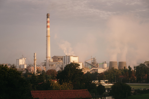 Large factory with smoke from chimneys under sunrise light